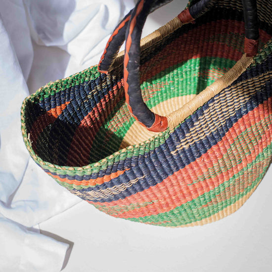 Colorful woven basket with patterned handles on a white background