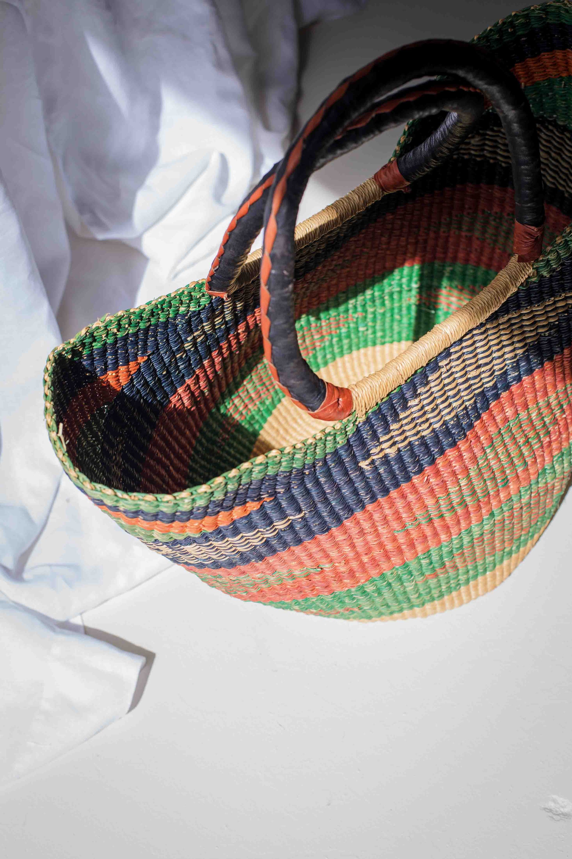 Colorful woven basket with patterned handles on a white background