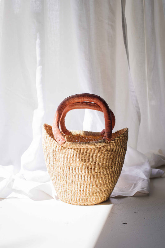 Woven basket with wooden handles on a white fabric background