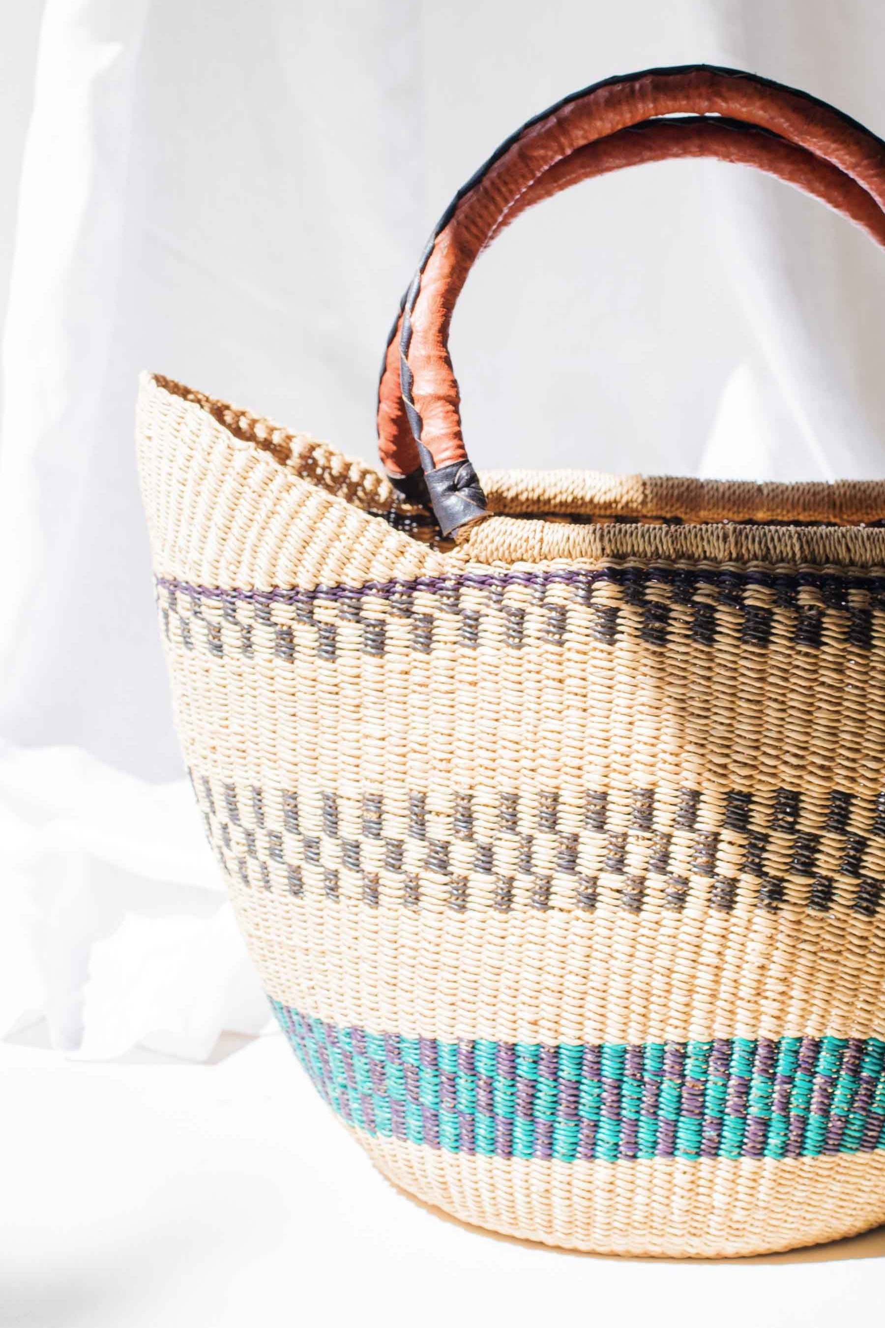 Woven basket with wooden handles on a white background