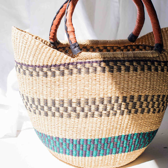 Woven basket with brown handles on a white background