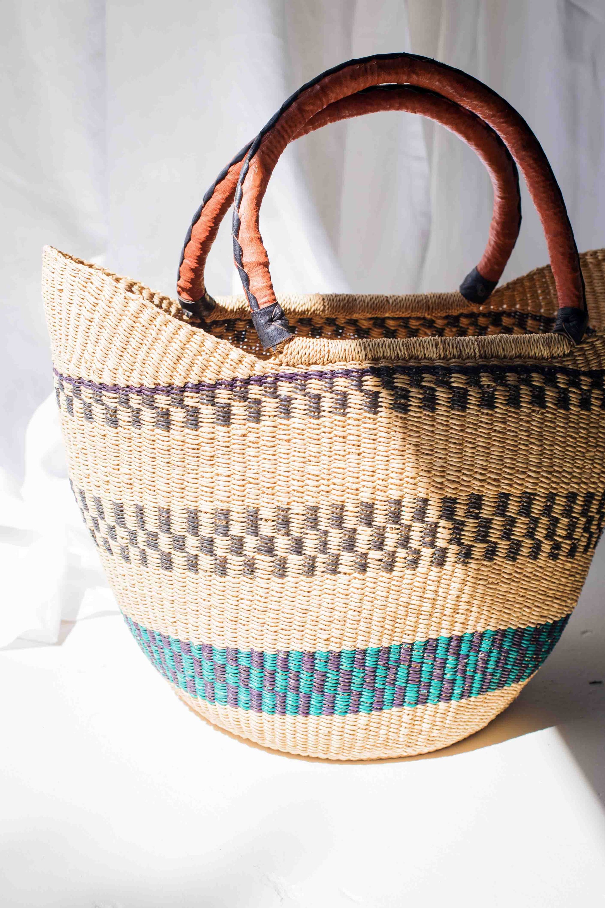 Woven basket with brown handles on a white background