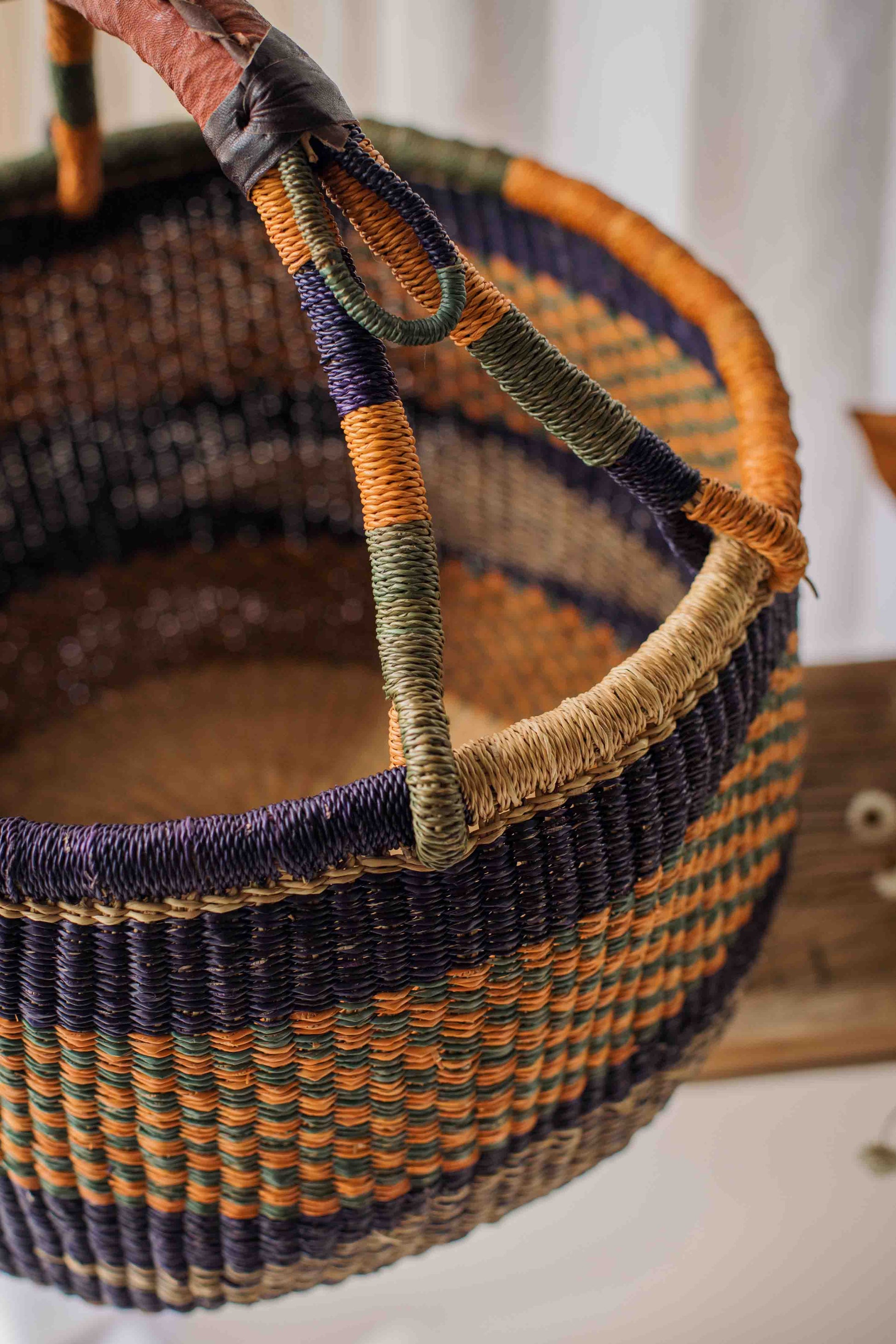 Woven basket with multicolored handle on a neutral background