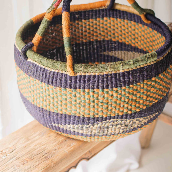 Woven basket with colorful handles on a wooden surface