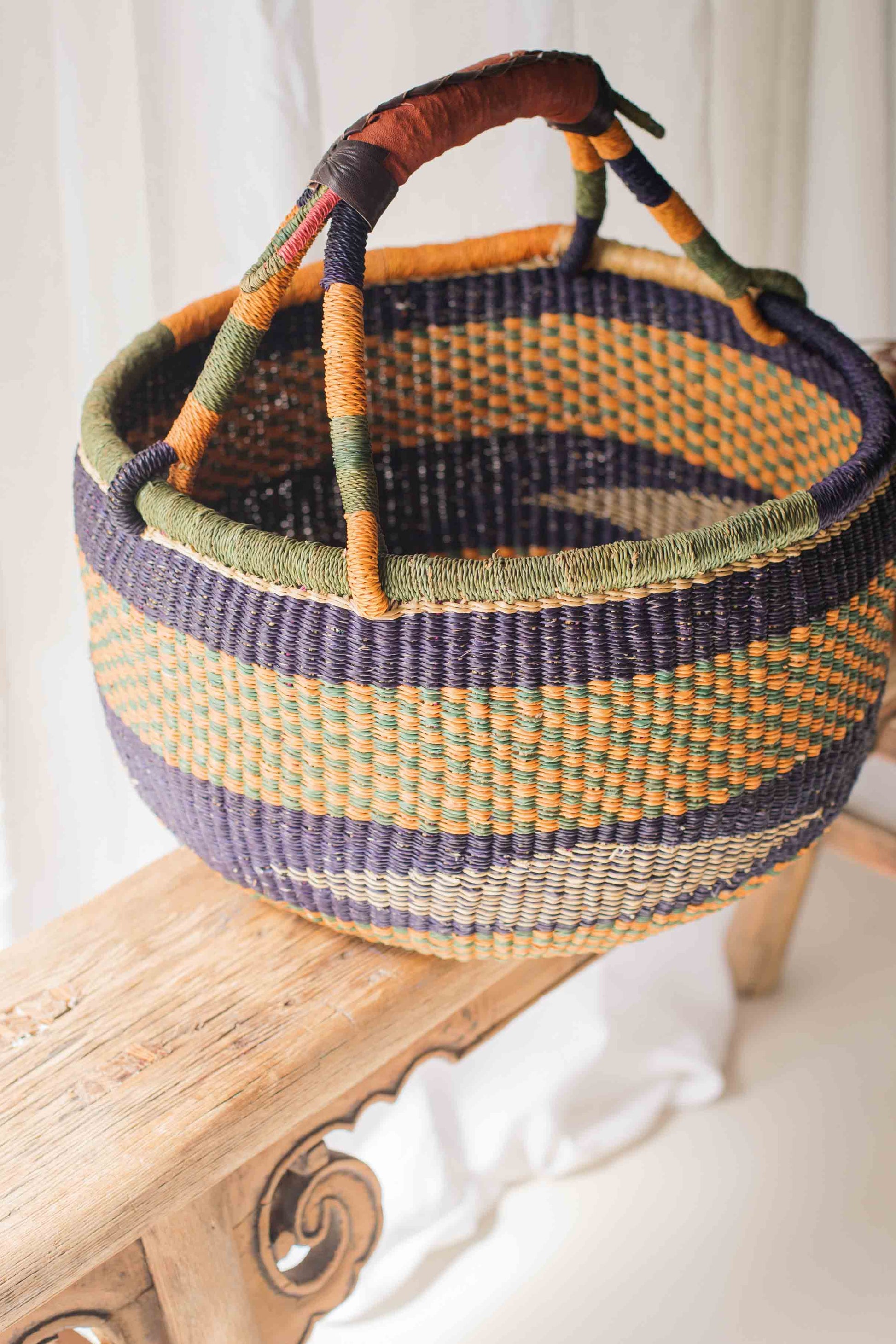 Woven basket with colorful handles on a wooden surface