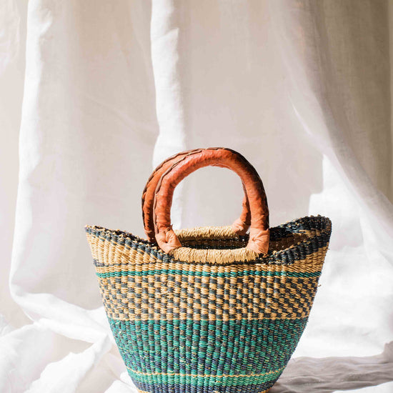 Woven handbag with brown handles on a white background