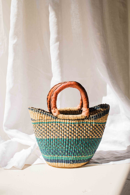 Woven handbag with brown handles on a white background
