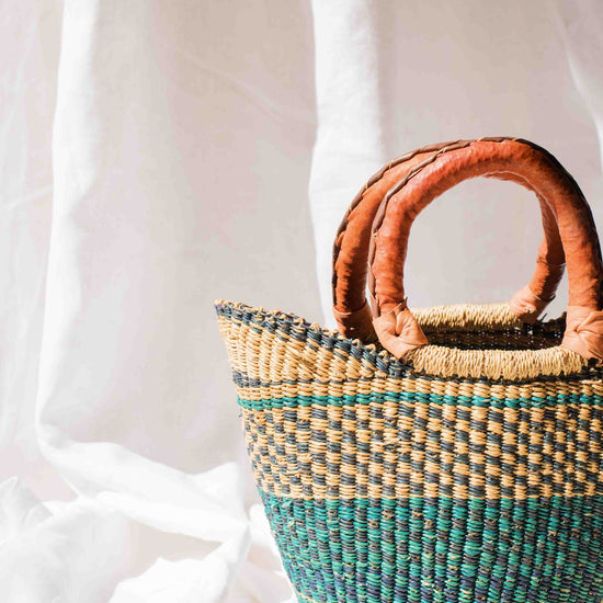 Woven basket with brown handles on a white background