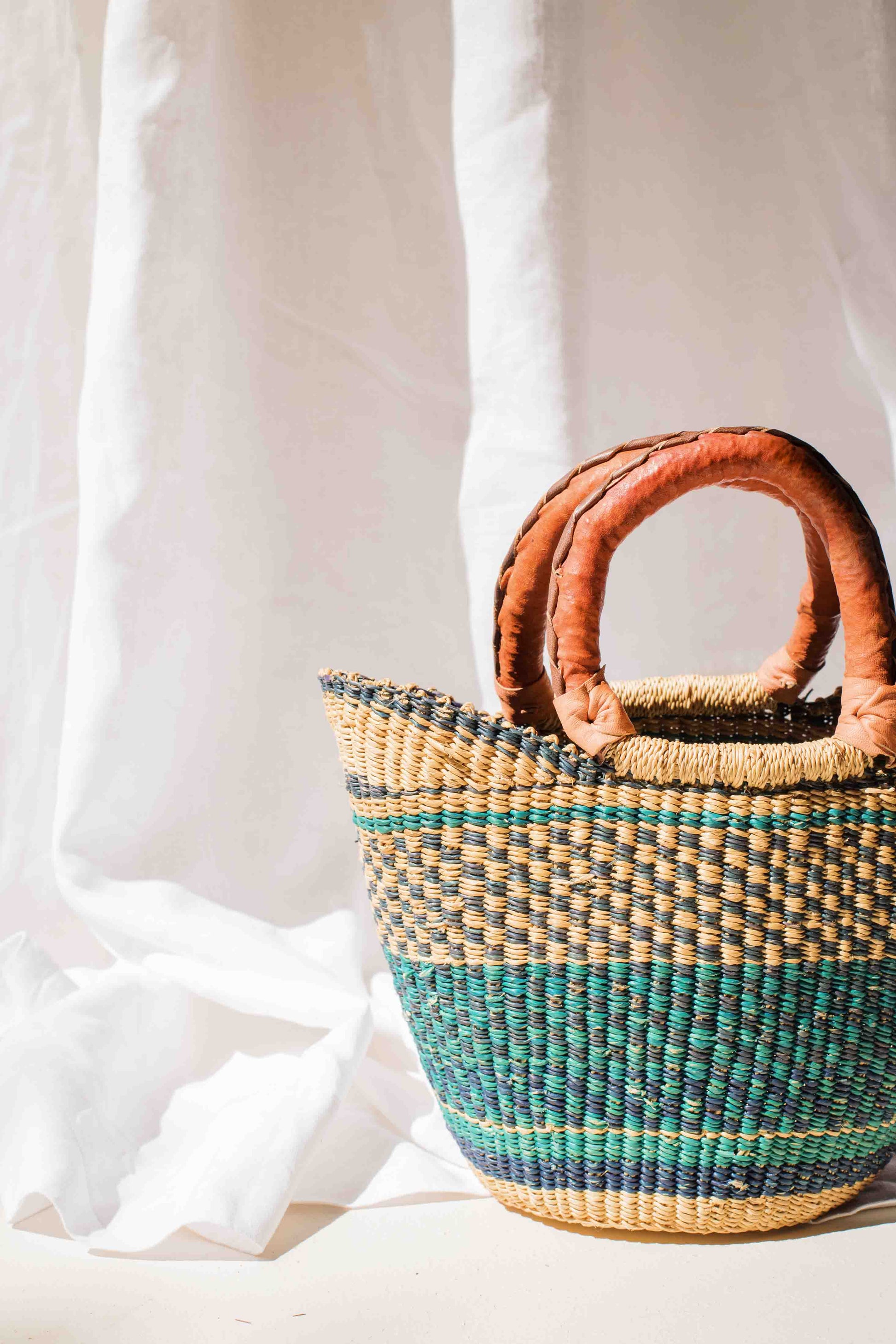 Woven basket with brown handles on a white background