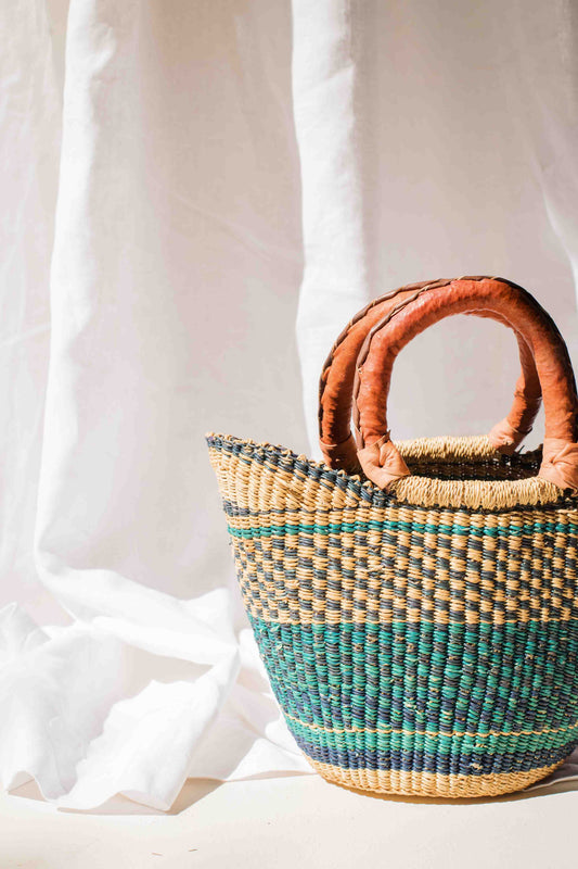 Woven basket with brown handles on a white background