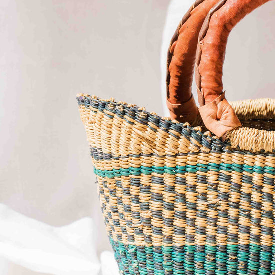 Woven handbag with brown handles on a white background