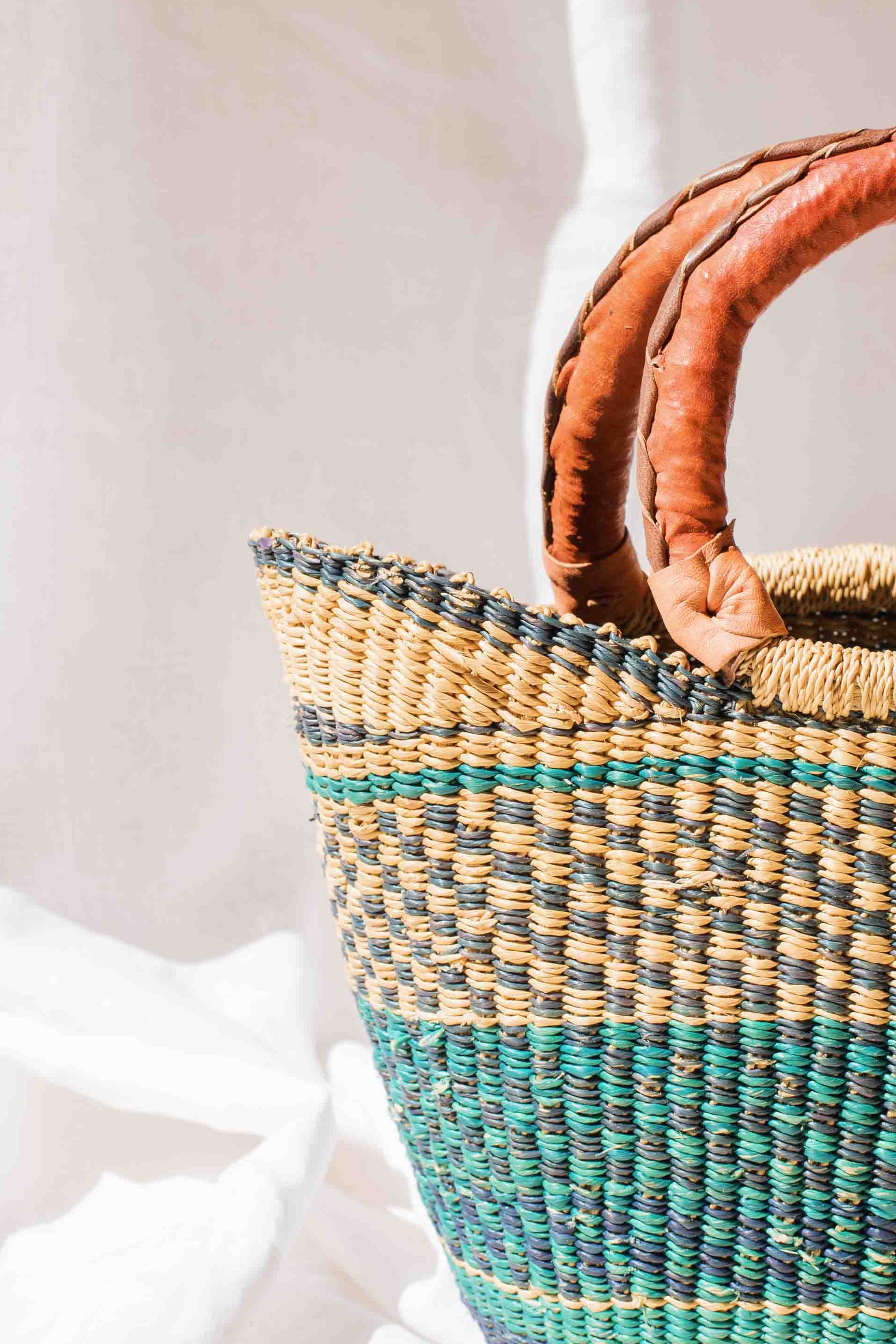 Woven handbag with brown handles on a white background