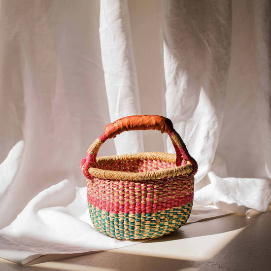 Woven basket with a handle on a light fabric background