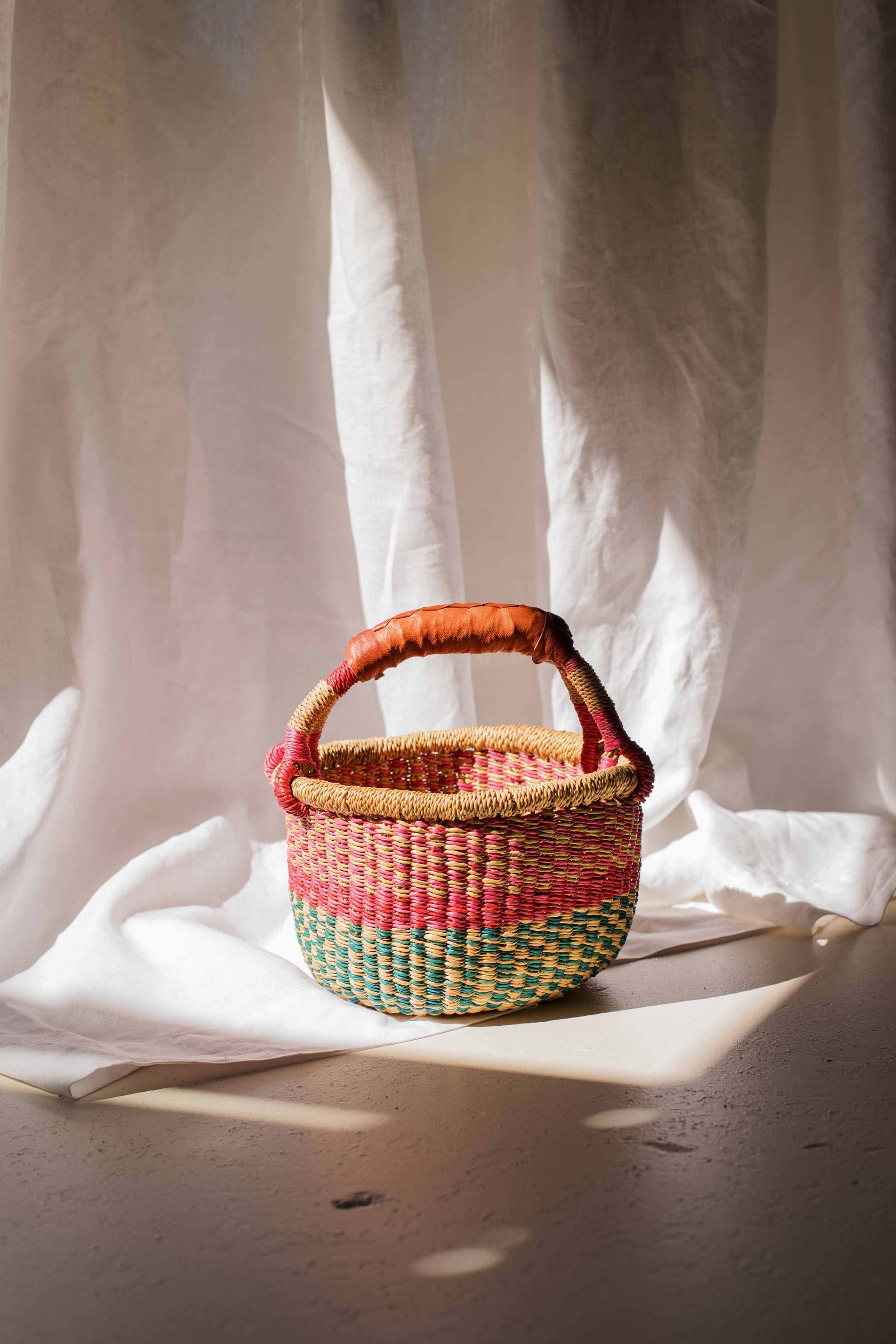 Woven basket with a handle on a light fabric background