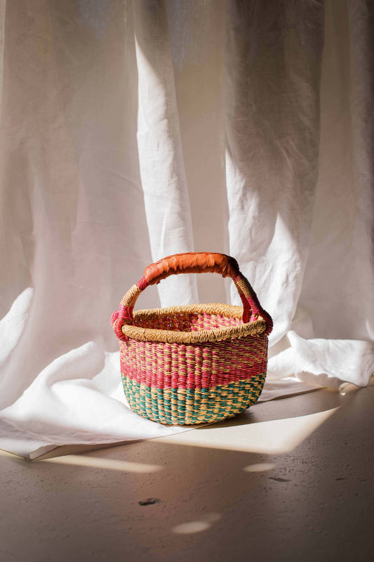 Woven basket with a handle on a light fabric background