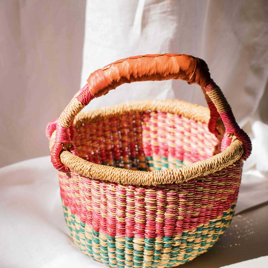 Woven basket with a colorful handle on a light background