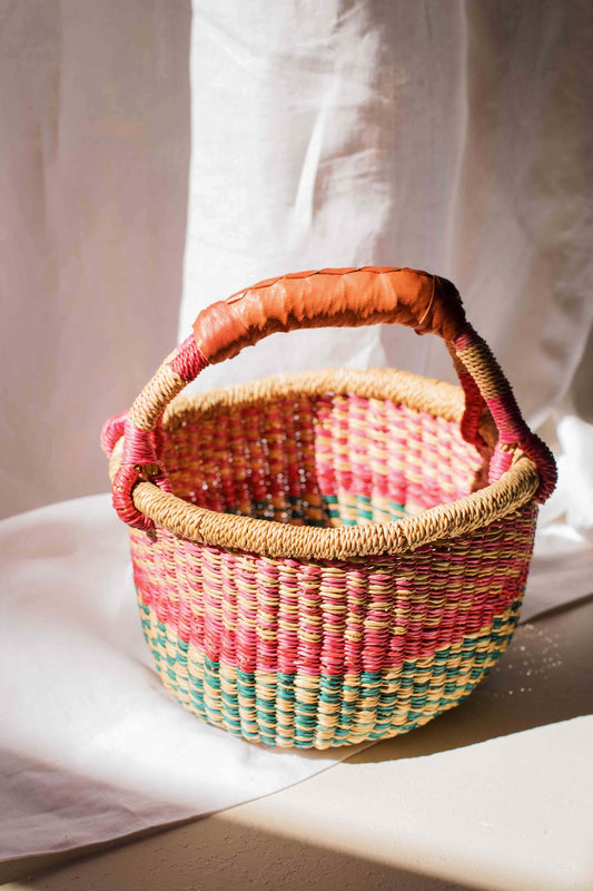 Woven basket with a colorful handle on a light background