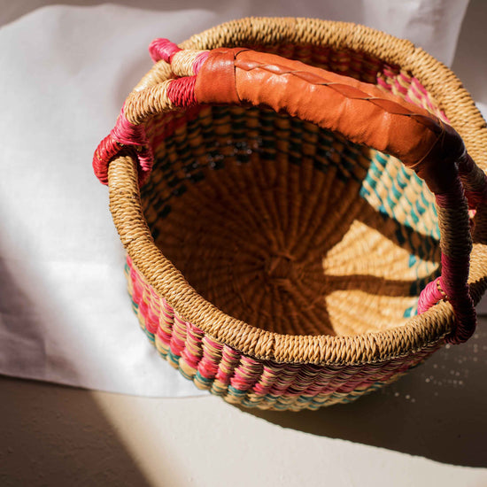 Woven basket with colorful fabric trim on a white surface
