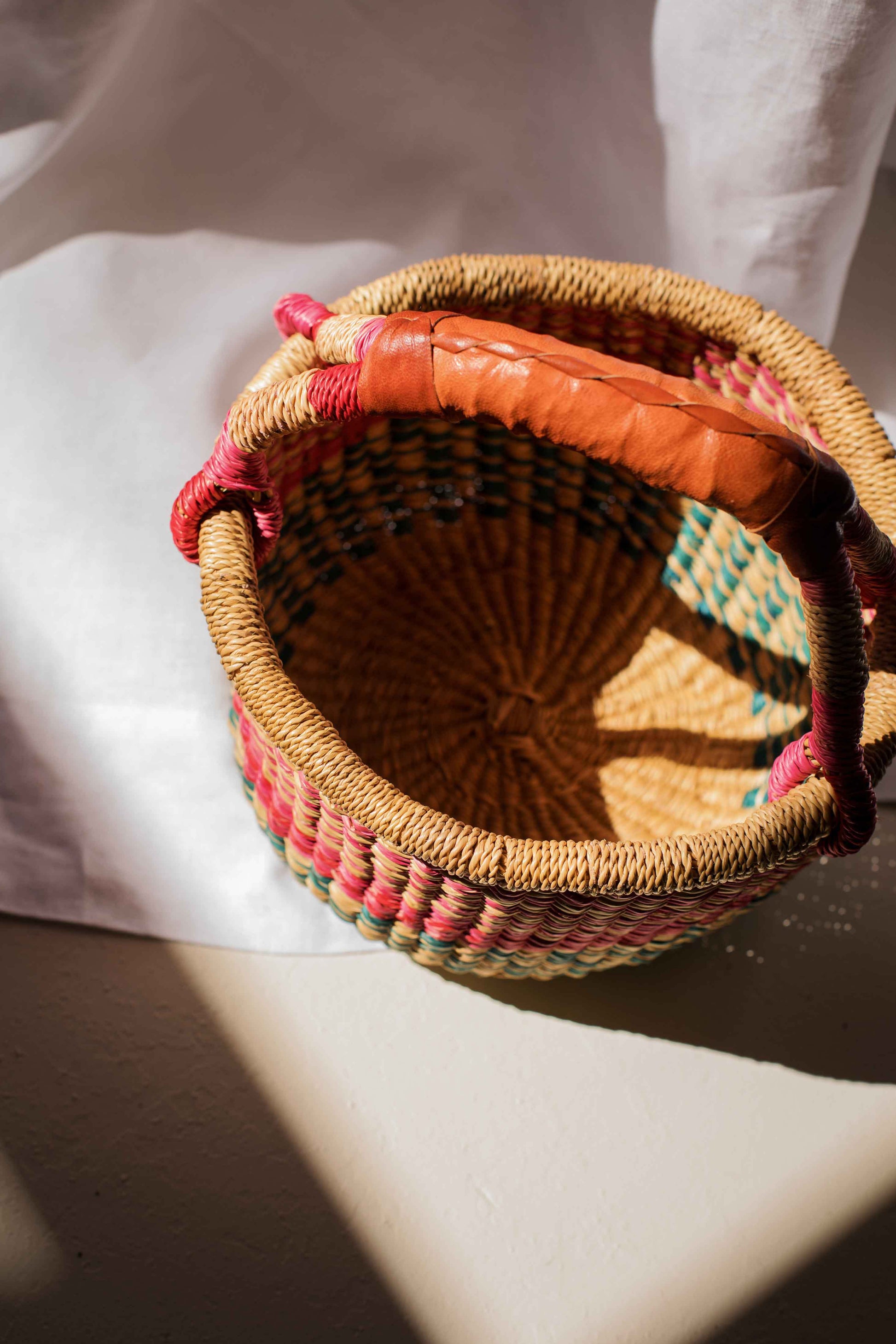 Woven basket with colorful fabric trim on a white surface