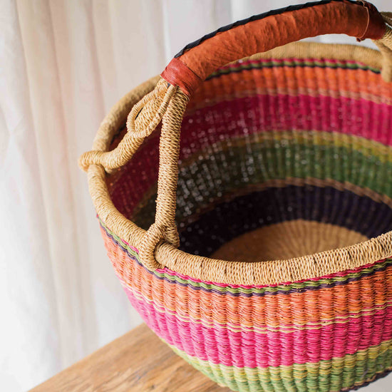Colorful woven basket with a handle on a wooden surface