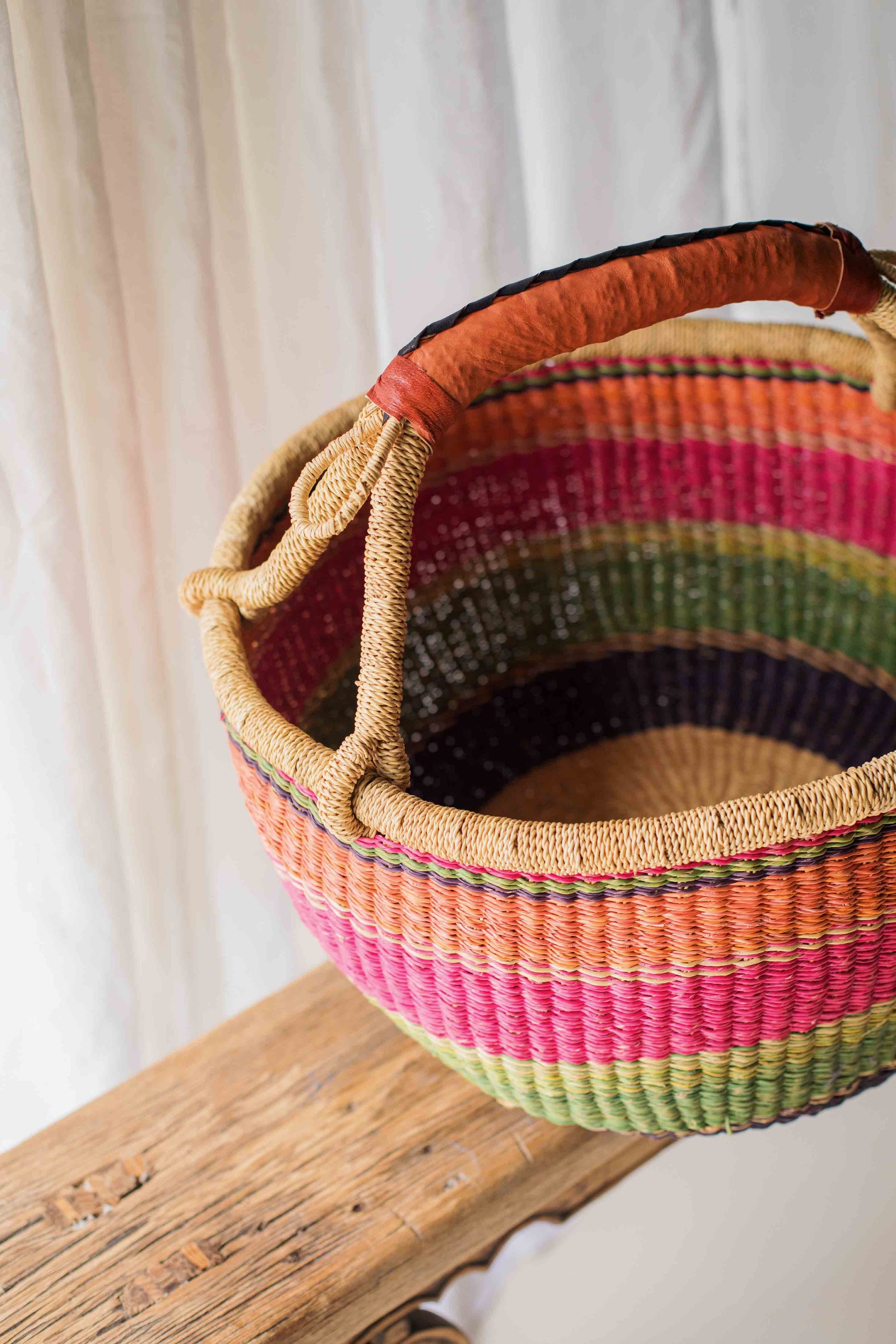 Colorful woven basket with a handle on a wooden surface