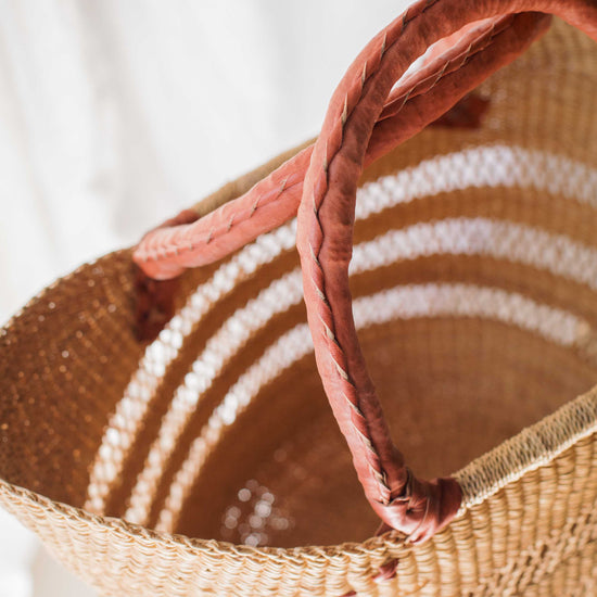 Woven basket with a pink handle on a white background