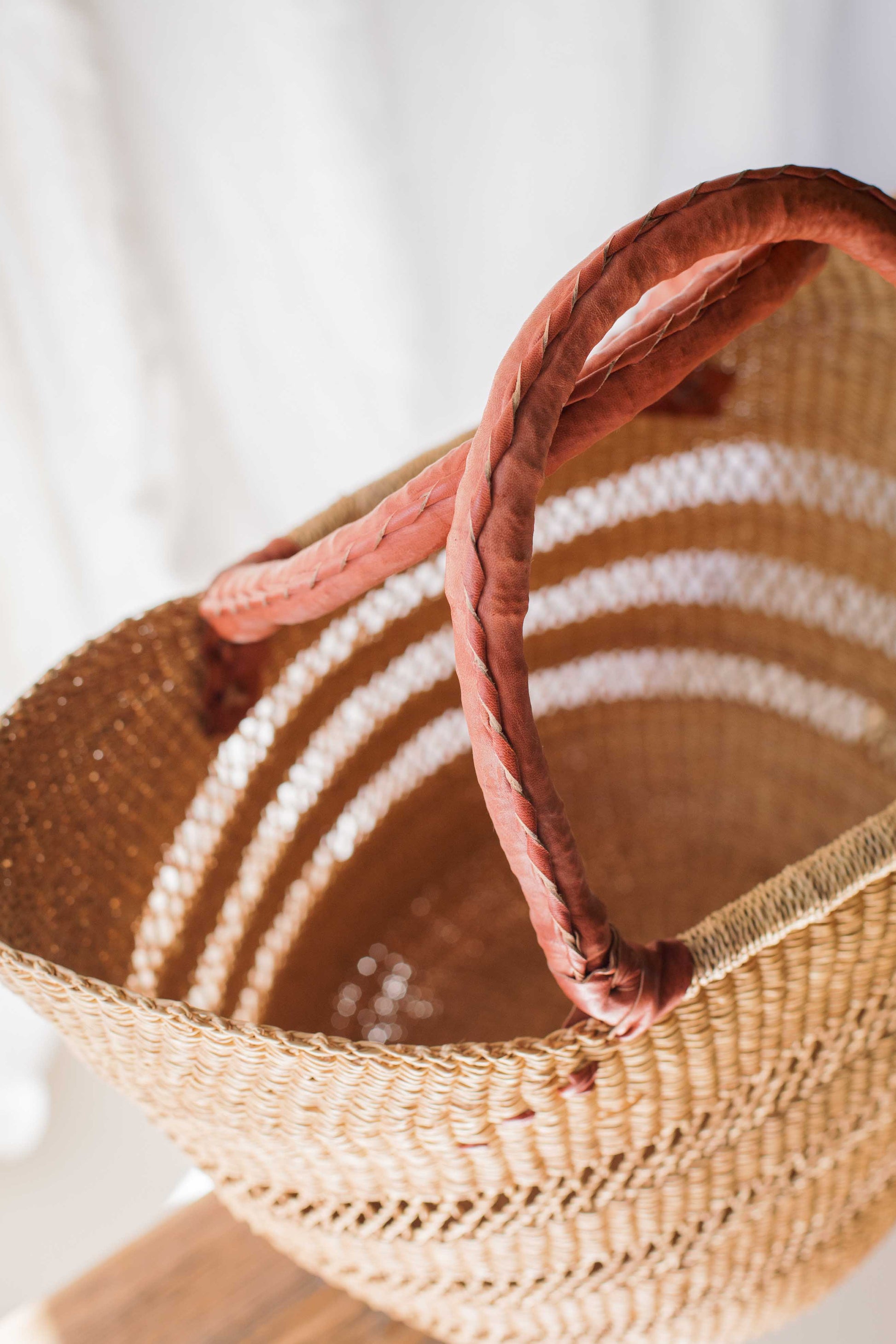 Woven basket with a pink handle on a white background