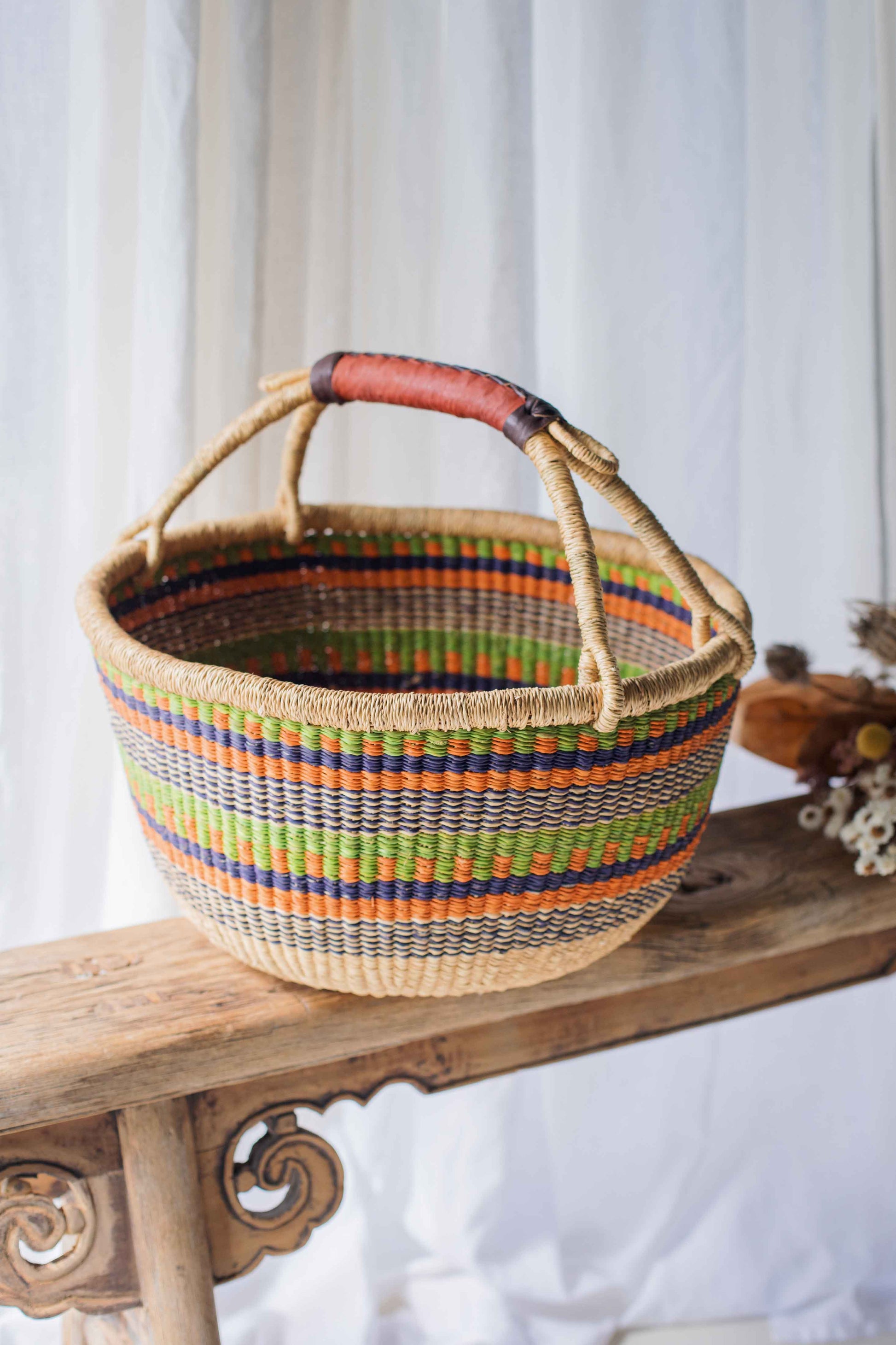 Colorful woven basket with a striped pattern on a wooden surface.