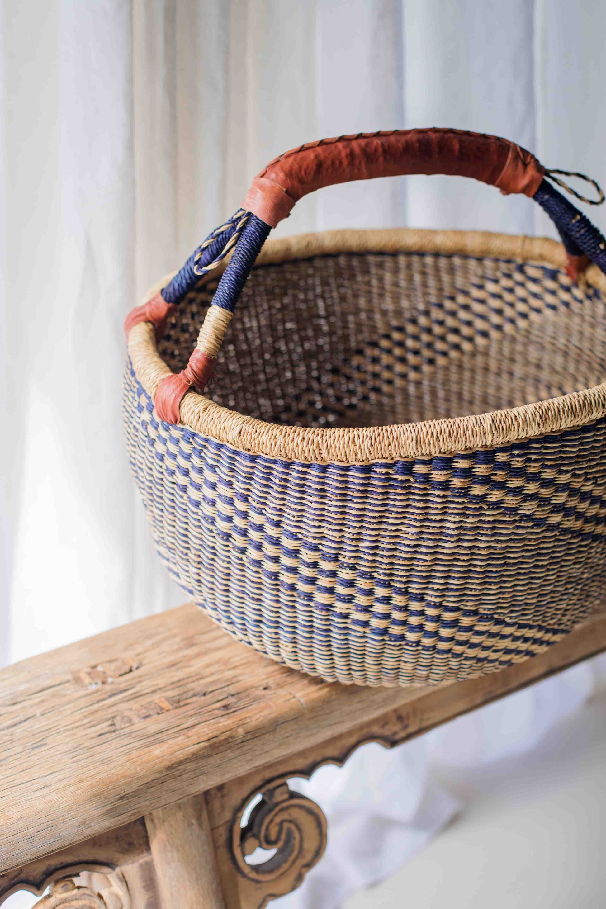 Woven basket with decorative handles on a wooden surface
