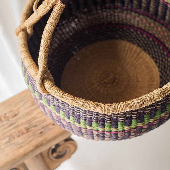 Woven basket with a colorful pattern on a wooden stand