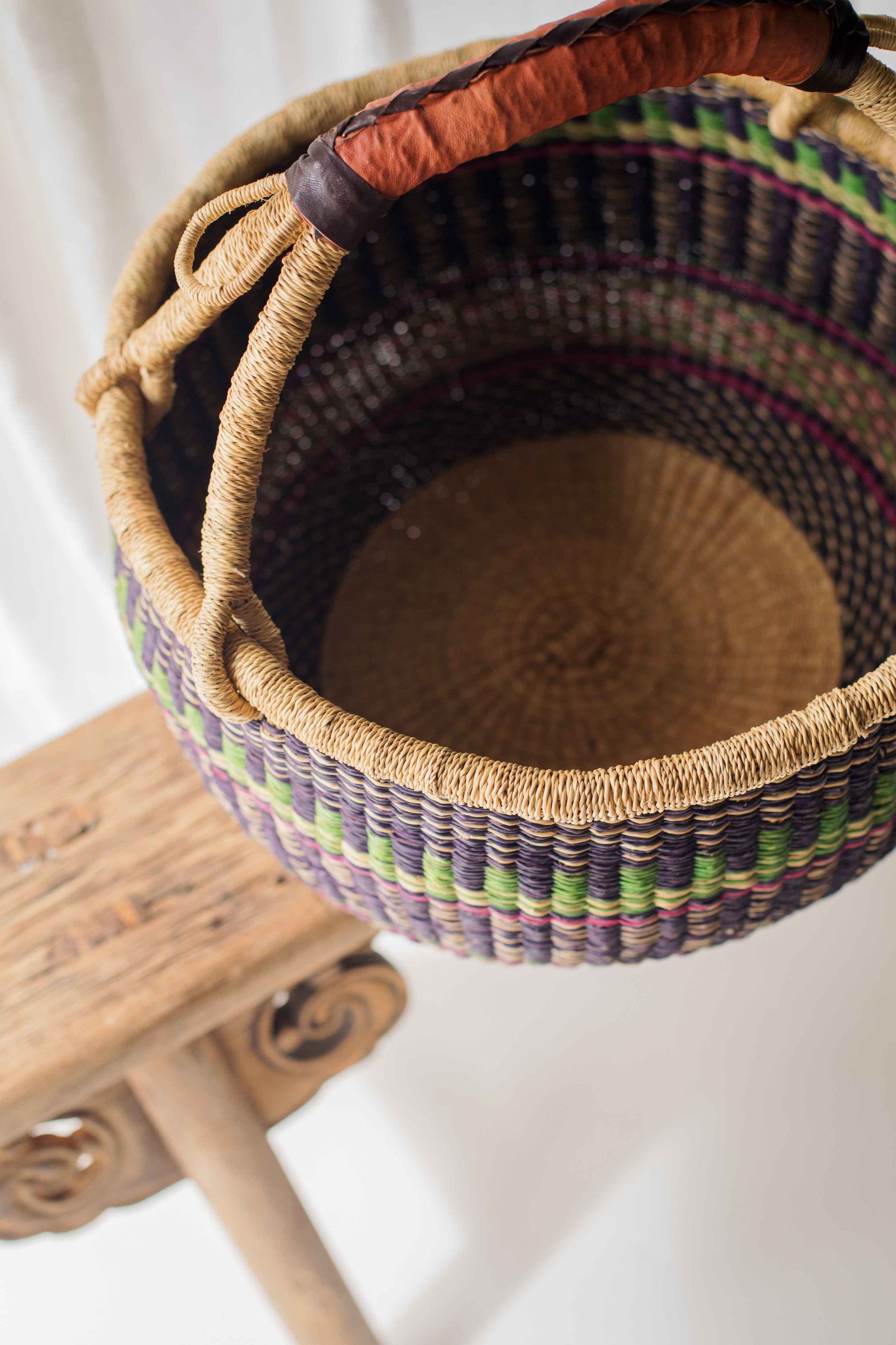 Woven basket with a colorful pattern on a wooden stand