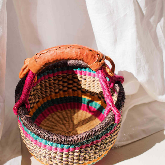 Multicolored woven basket with a brown lid on a white background