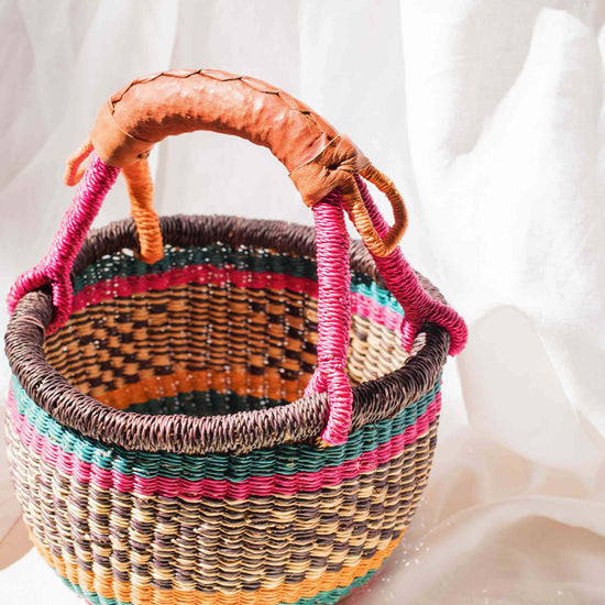 Colorful woven basket with a handle on a white background