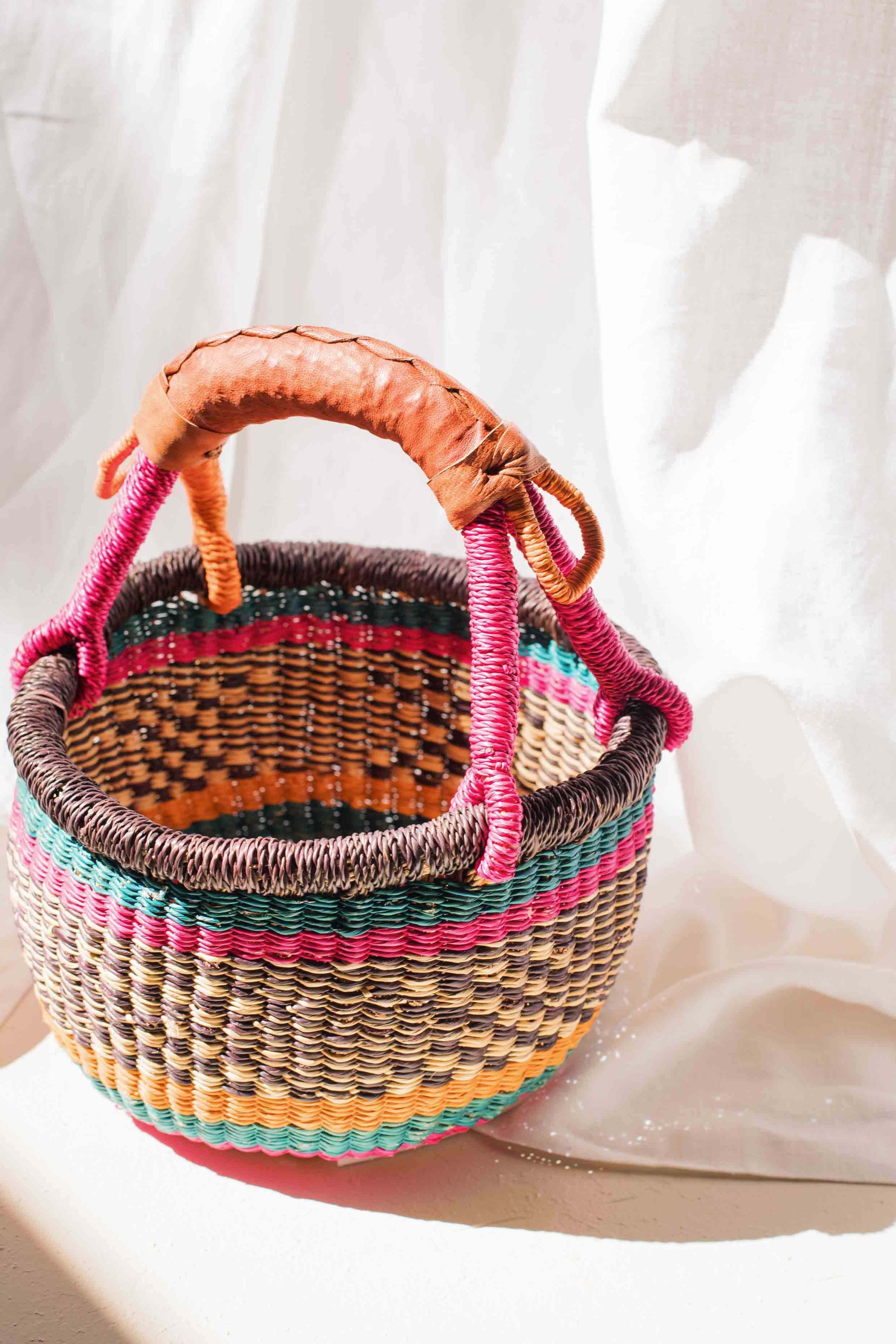Colorful woven basket with a handle on a white background