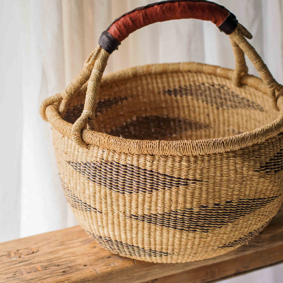 Woven basket with a red handle on a wooden surface