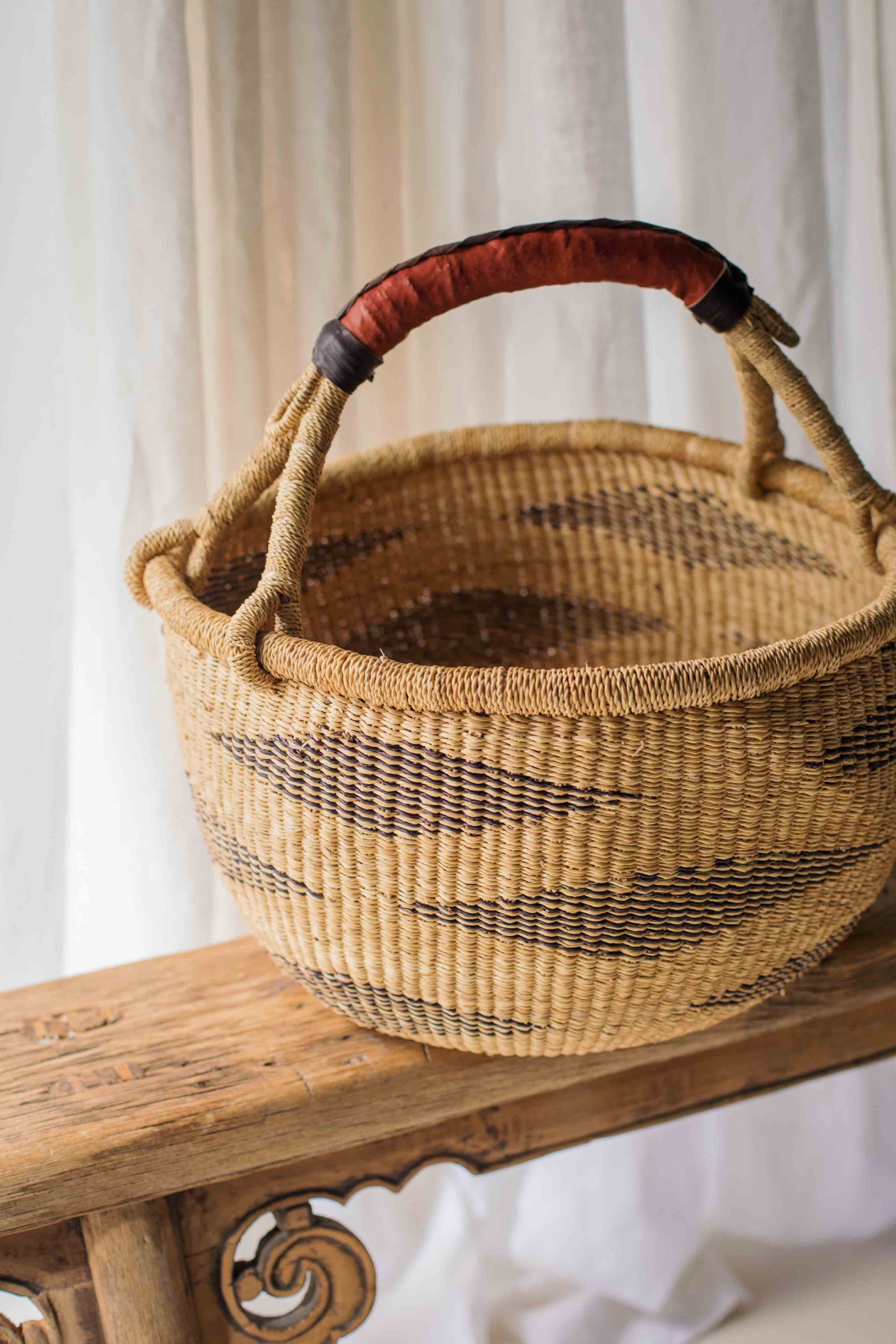 Woven basket with a red handle on a wooden surface