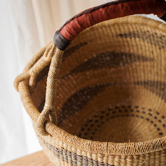 Woven basket with a red handle on a wooden surface