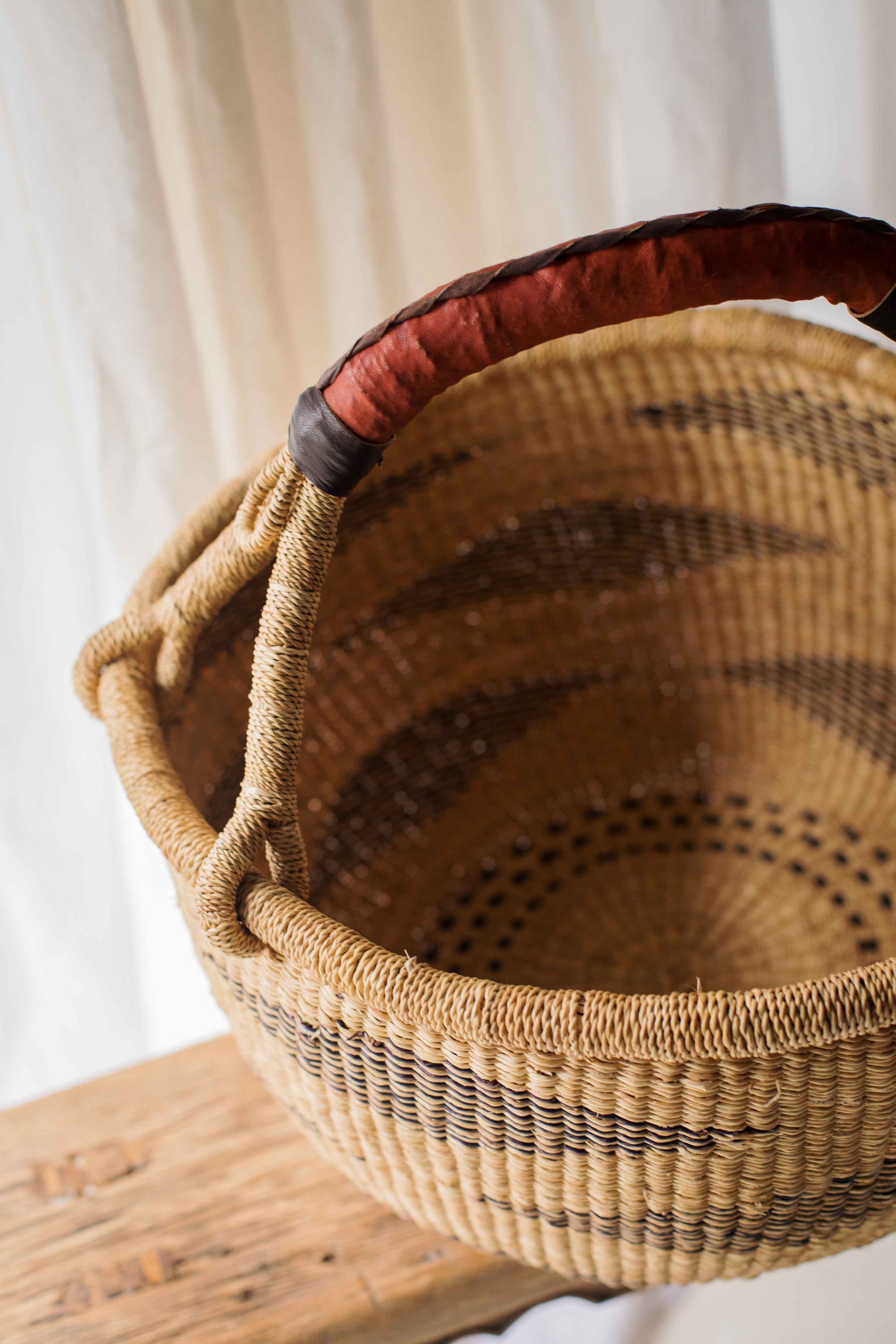 Woven basket with a red handle on a wooden surface