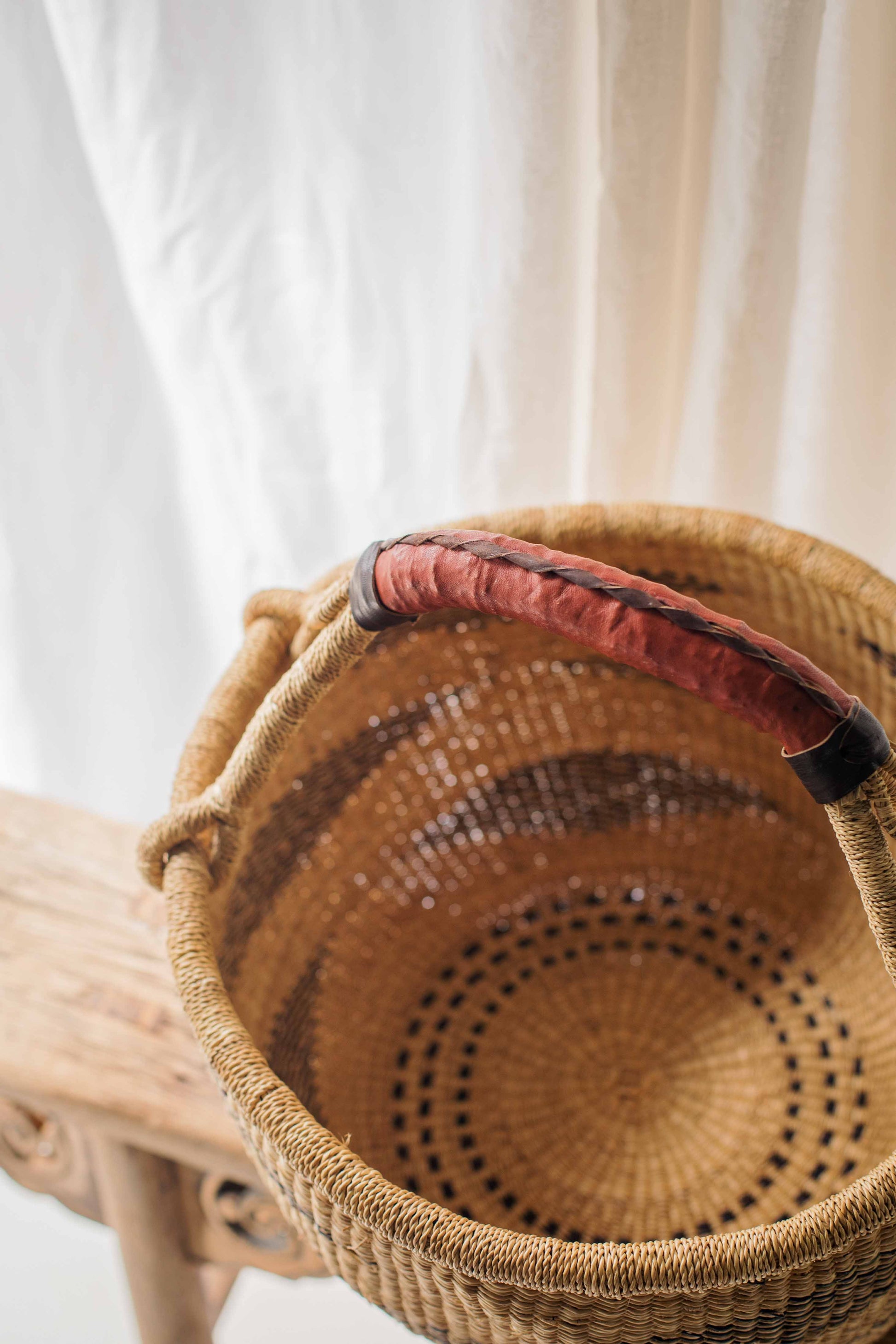 Woven basket with a red handle on a light wooden surface