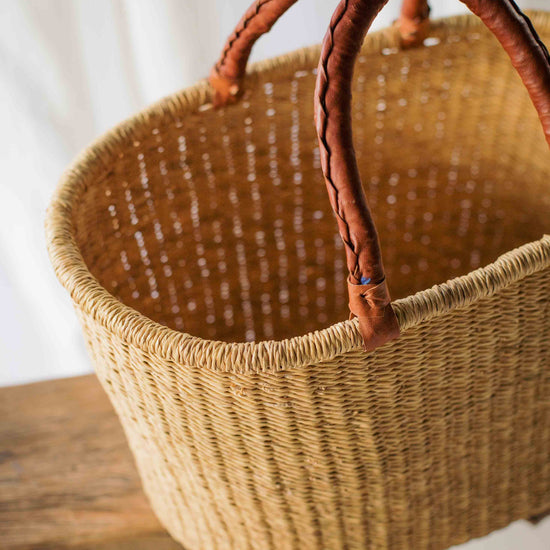 Woven basket with leather handles on a wooden surface