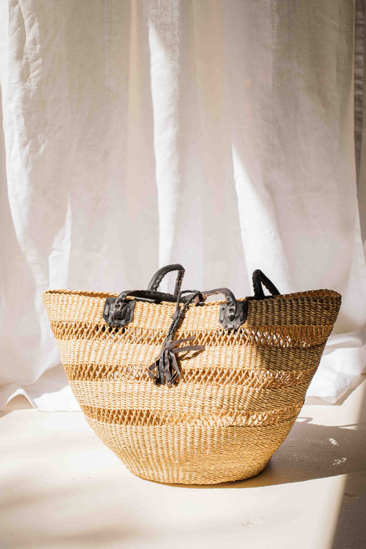 Woven basket with black straps on a white background