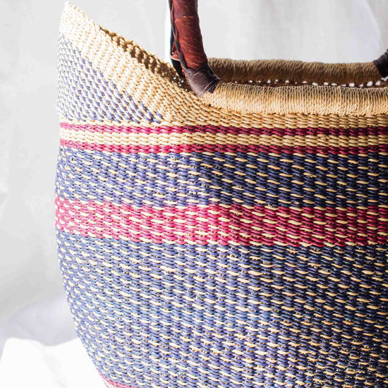 Woven basket with striped pattern and wooden handles on a white background