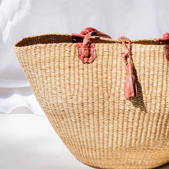 Woven basket with pink tassels on a white background