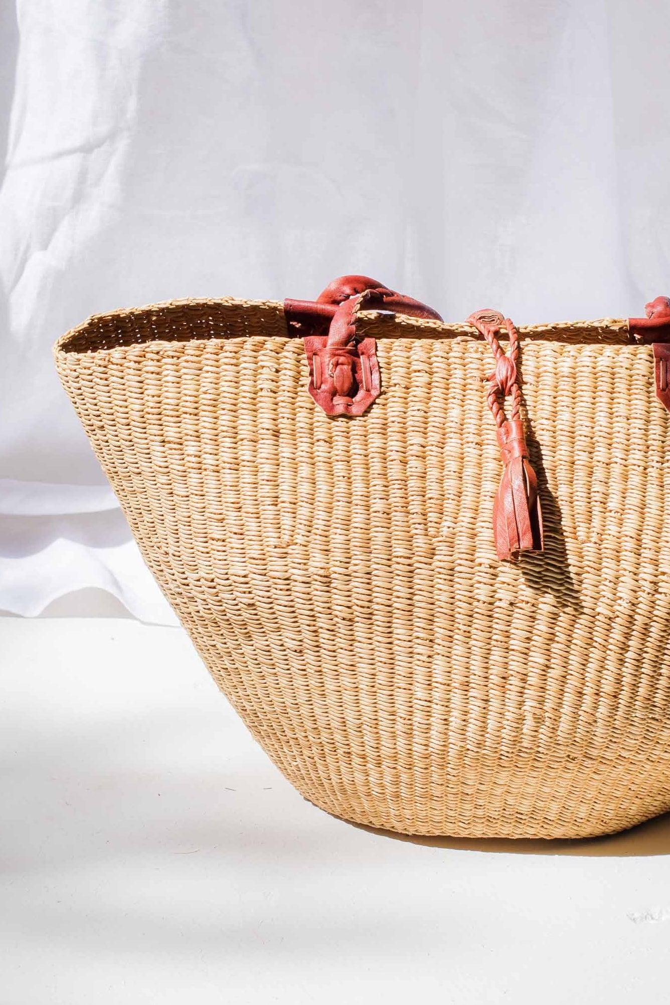 Woven basket with pink tassels on a white background