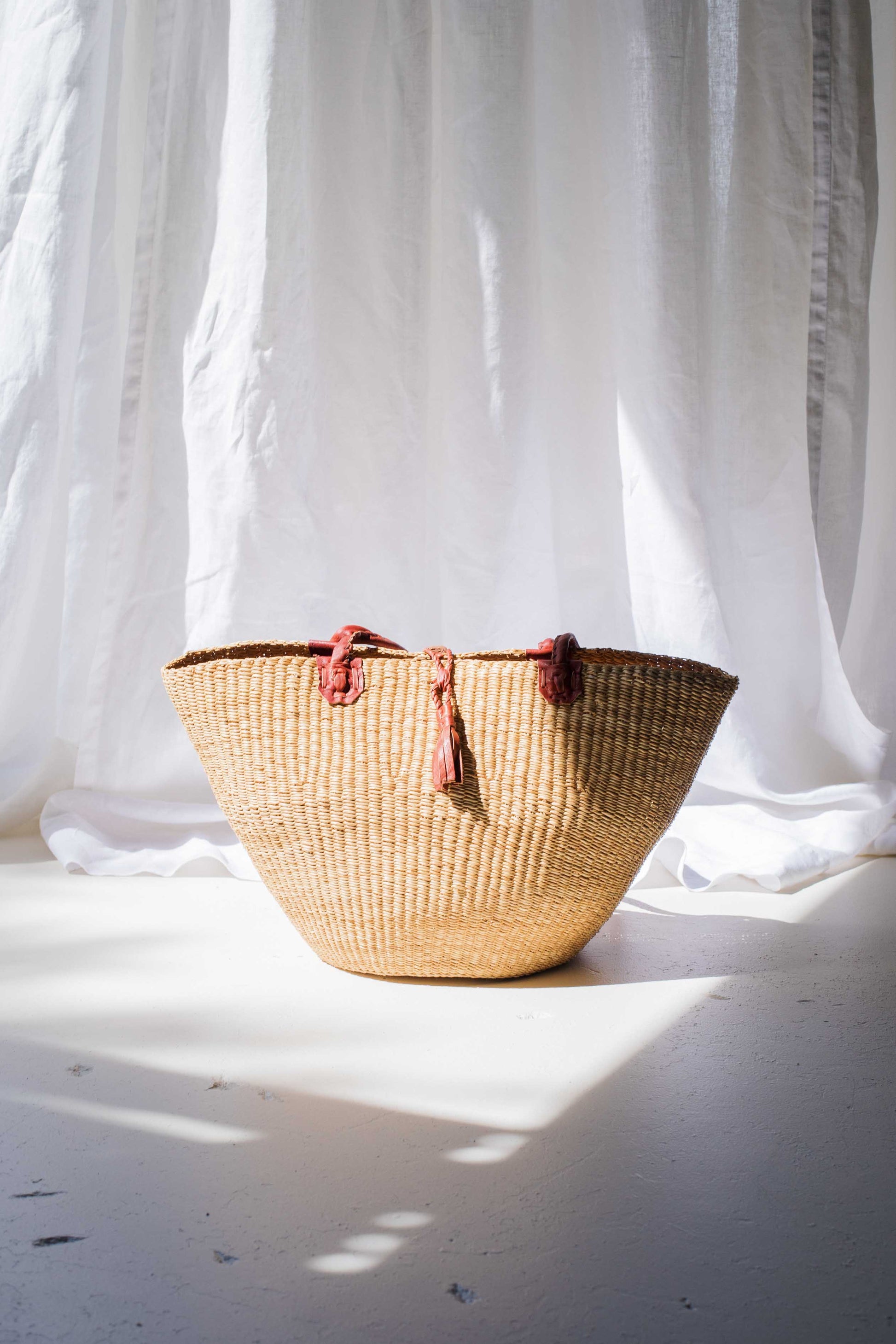 Woven basket with tassels on a light background