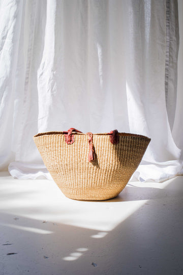 Woven basket with tassels on a light background