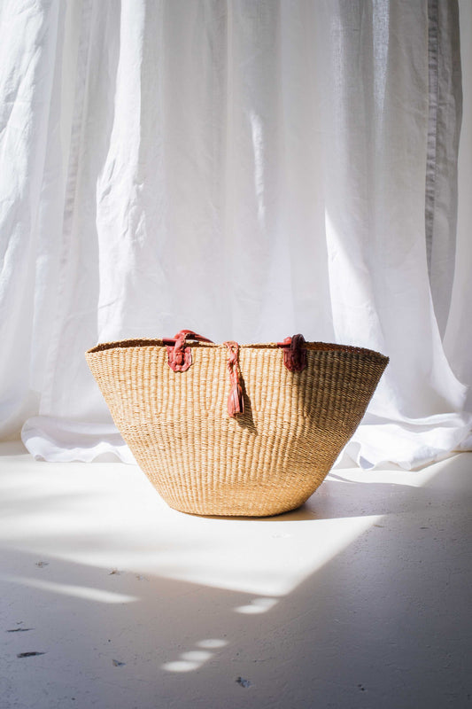Woven basket with tassels on a light background