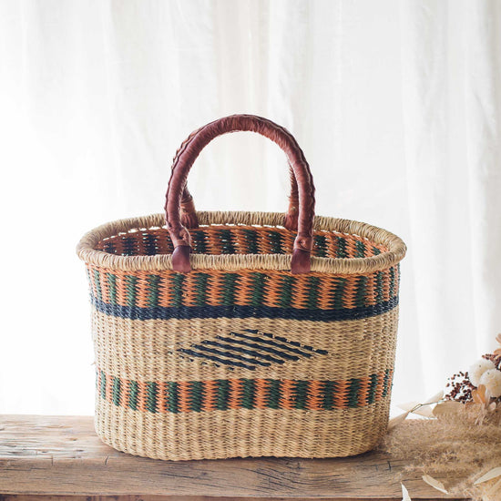 Woven basket with striped pattern on a wooden surface with a white curtain background