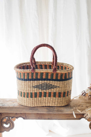 Woven basket with striped pattern on a wooden surface with a white curtain background