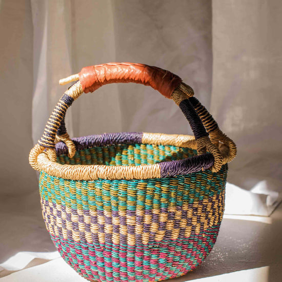 Woven basket with multicolored handle on a light surface